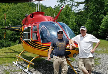 Bill Macchio standing next to a helicopter with son Drew, the pilot